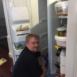 Fridge repair technician working inside refrigerator